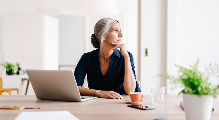 woman sitting at her computer and gazing out the window thinkiing about owning her sacramento home