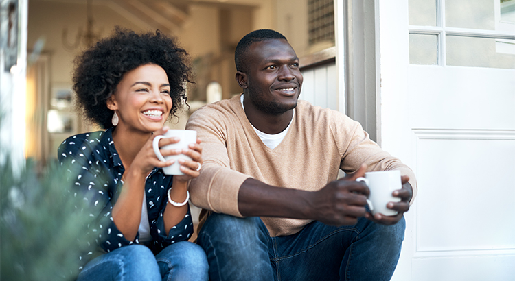 woman and man sitting on the porch holding cups